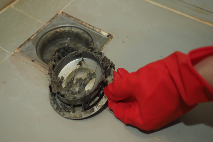 Shower drain clogged with full of hair and accumulated clogged grease.