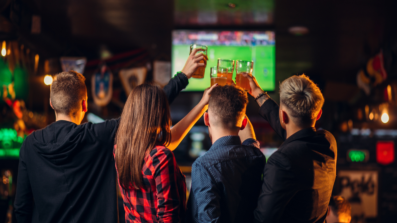 People Raising A Drink To Sports At A Sports Bar